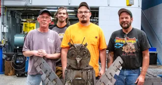 Team posing with metal sculpture at Metal Mania
