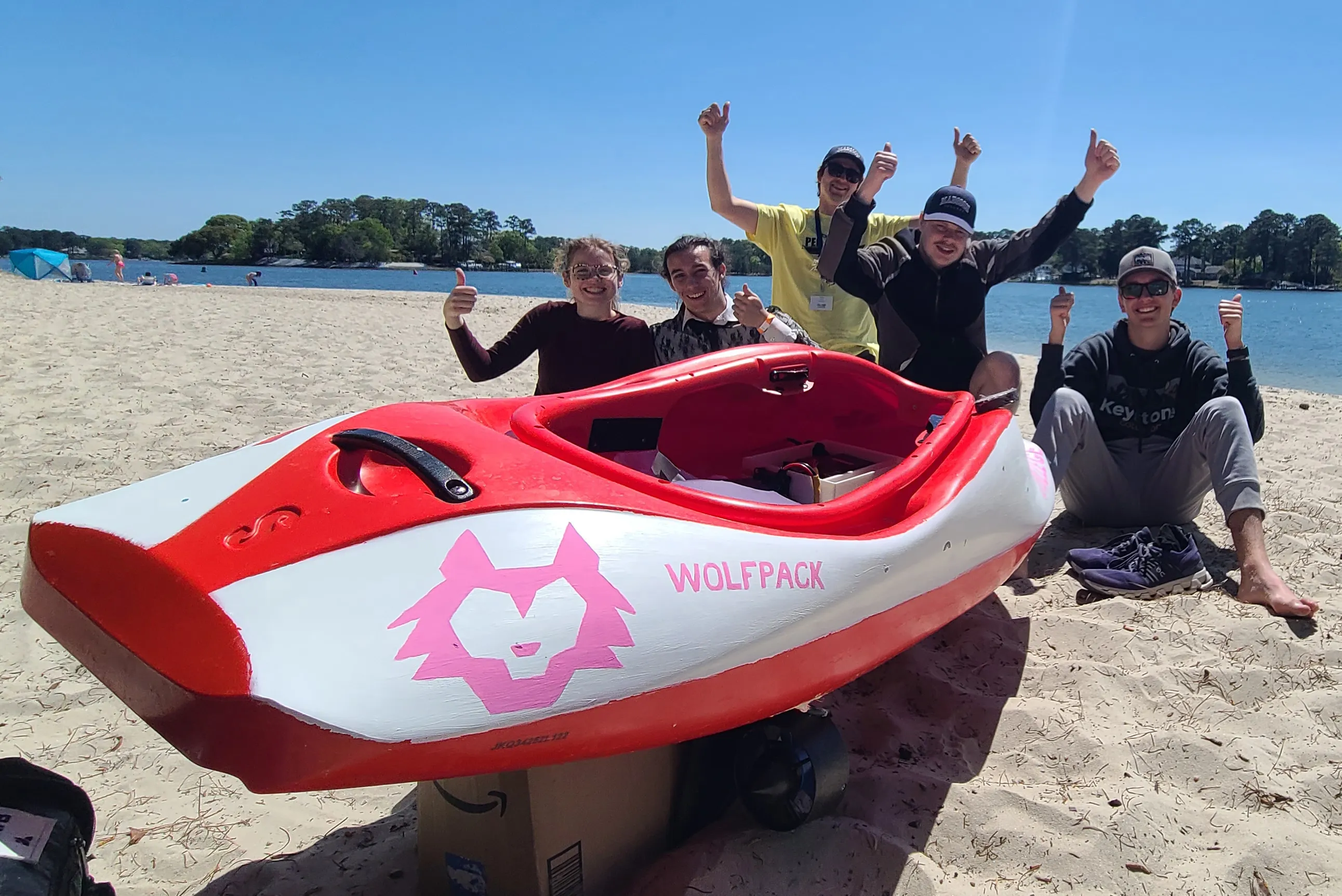 Photo of PEP team posing on a sand beach with their boat.