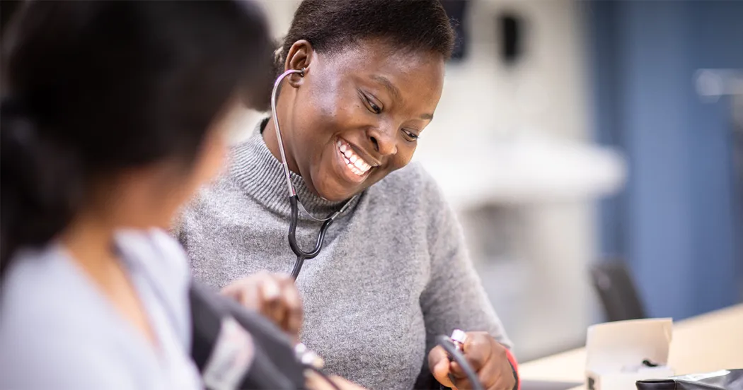 Nursing student smiling while practicing with stethoscope