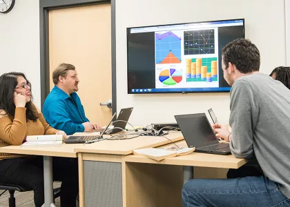 Students around a table reviewing a presentation