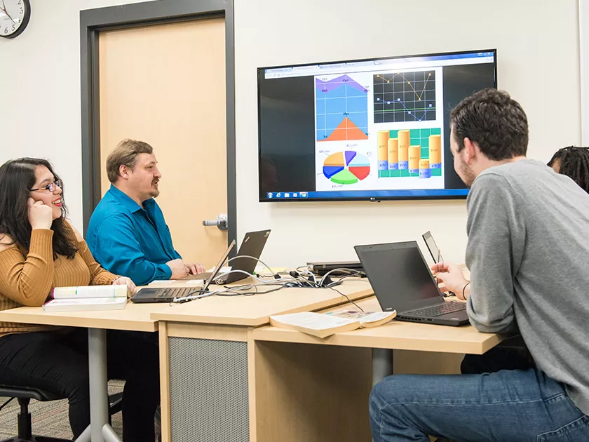 Students around a table reviewing a presentation