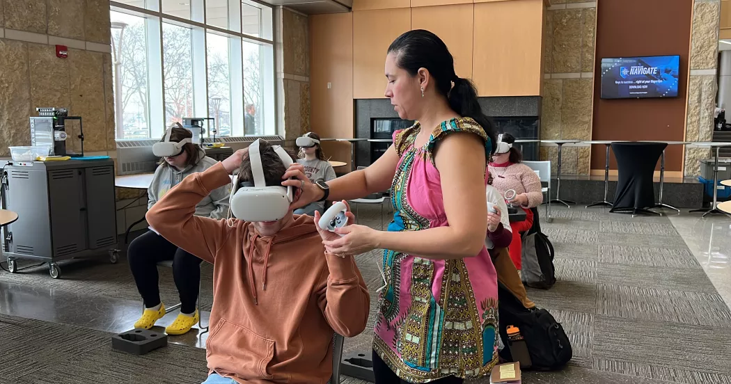 Madison College instructor Carolina Bailey helps a student with their VR headset.