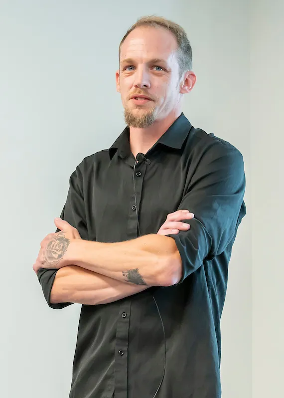headshot of darin wellons, person dressed in black, light hair, arms crossed
