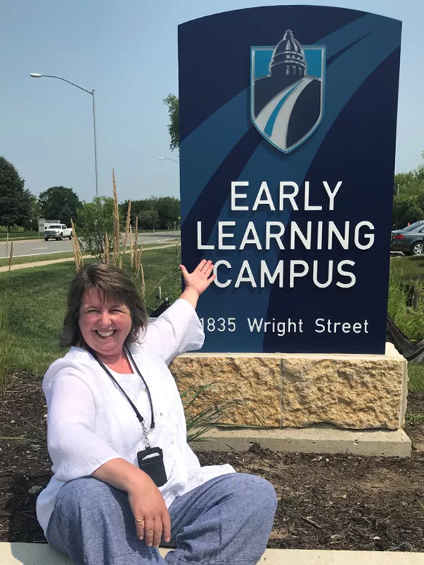 Staff member in front of the Early Learning Campus sign