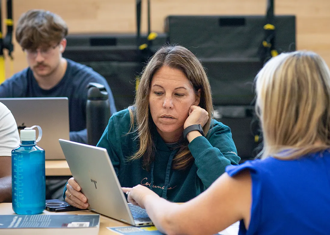 staff and student looking at laptop screen in rec classroom