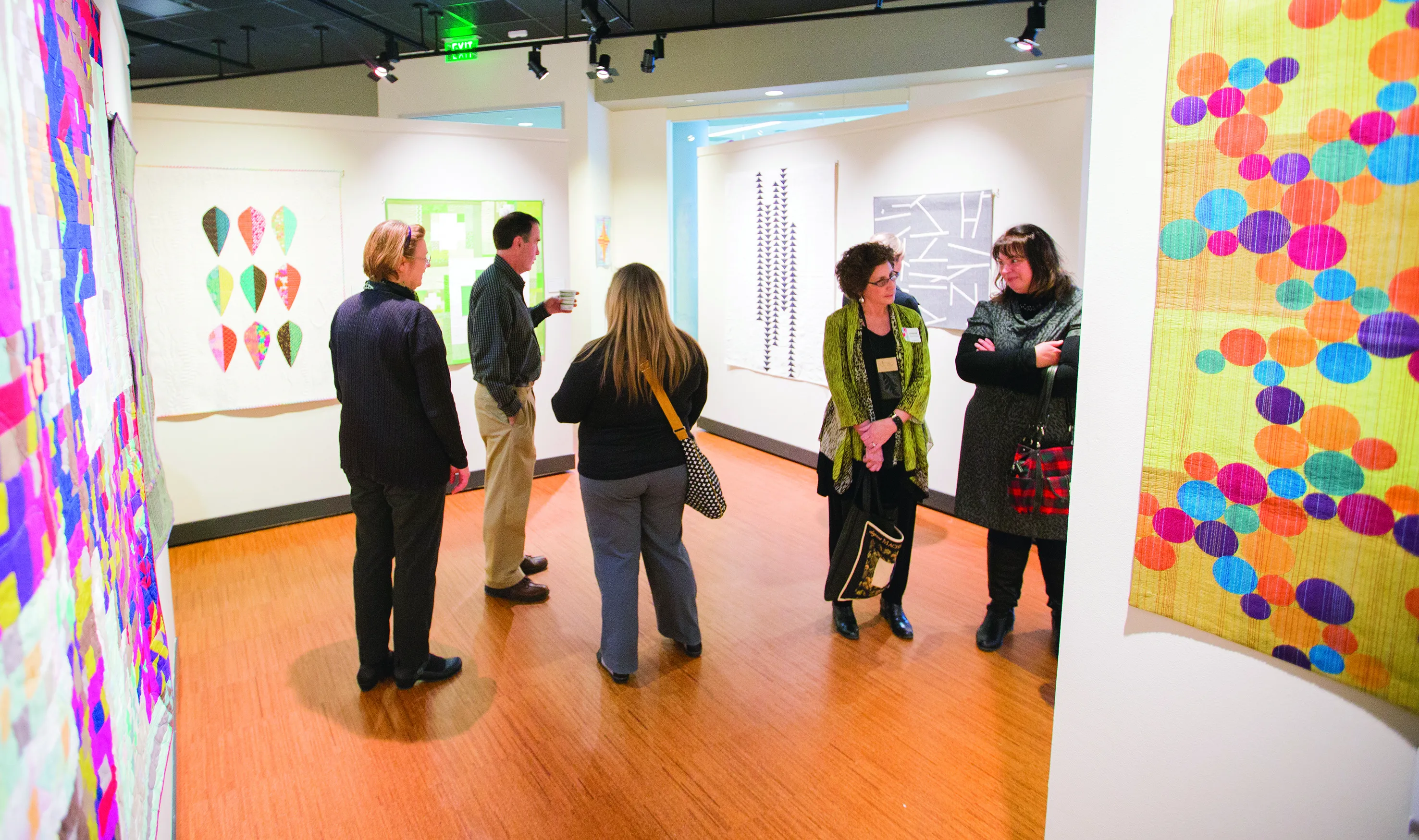 People standing in an the Gallery at Truax talking and looking at paintings on the wall.