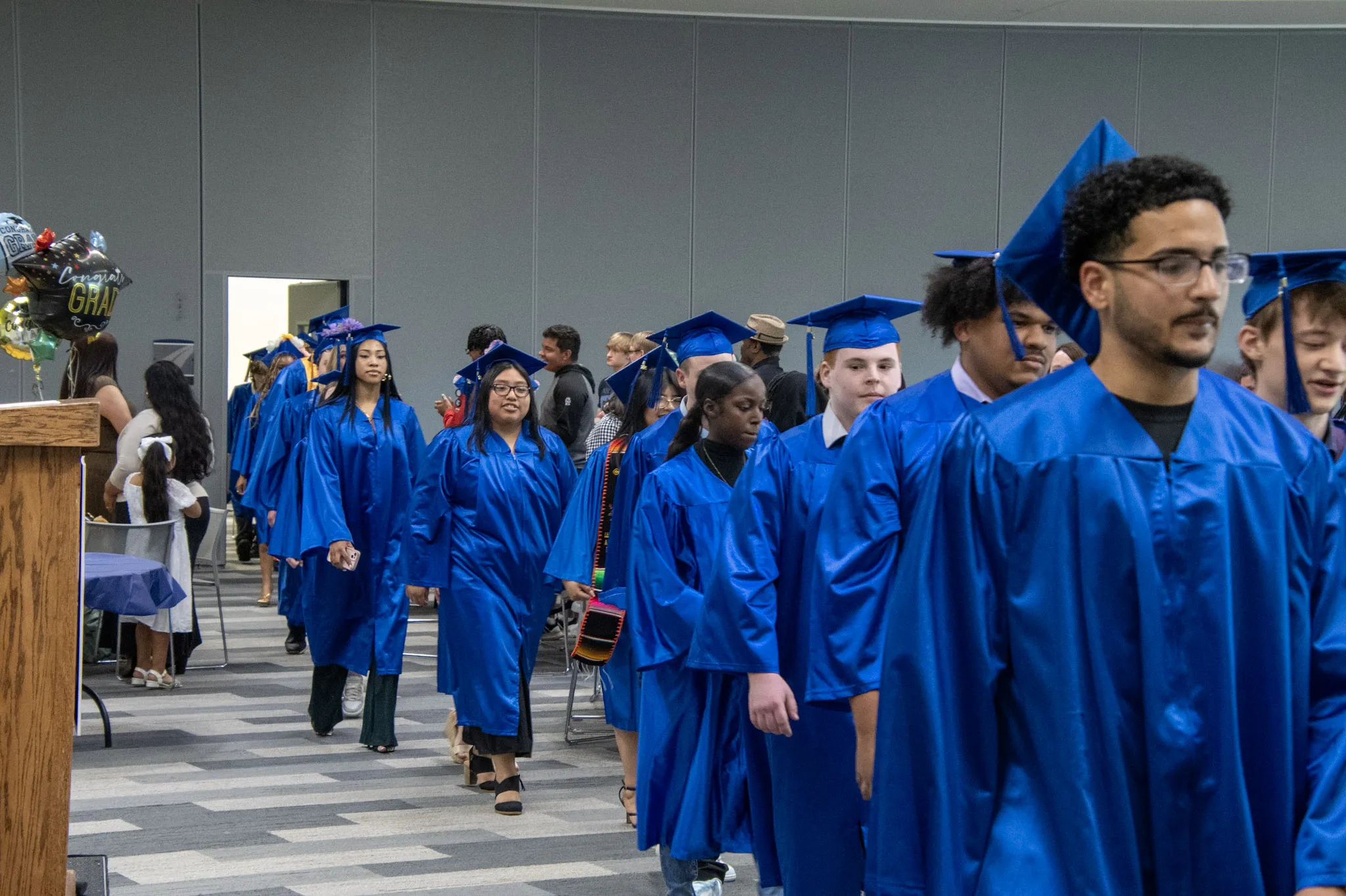 Gateway to College students in line to get their diploma at graduation ceremony, wearing blue caps and gown.