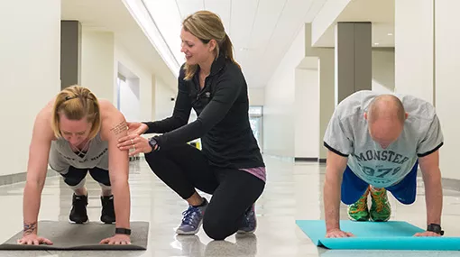 student assisting others in a yoga plank position