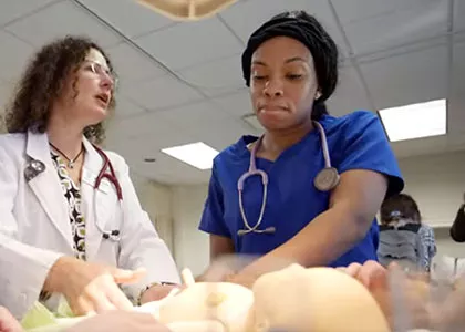 nursing student and instructor in lab practicing on medical mannequins