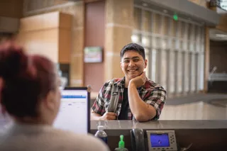 Student talking to person at Truax's service counter in atrium.
