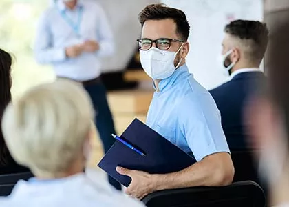 masked student standing in a group of students having informal conversations.