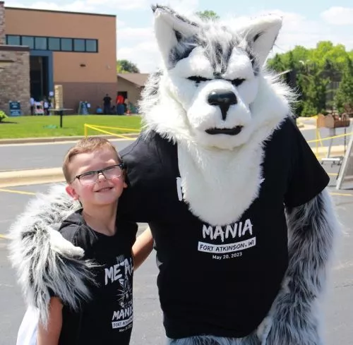 Madison College Wolfie poses with child at 2024 Metal Mania