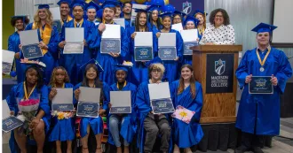 A group of Gateway College posing with their diplomas/certificates, dressed in blue caps and gowns.