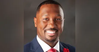 Close up headshot of Donald Dantzler, wearing a blue blazer, red tie. 