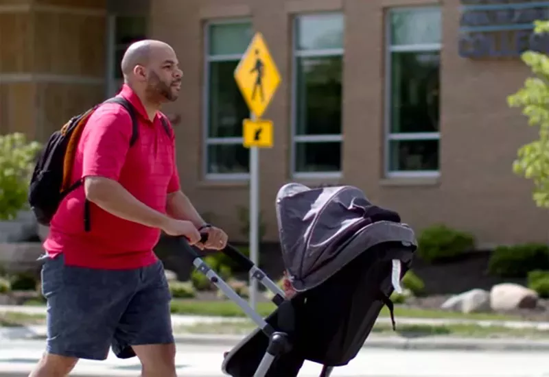 Person pushing stroller in front of Madison College building