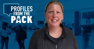 Angie Hoefs facing forward smiling with blue Madison College background behind her.