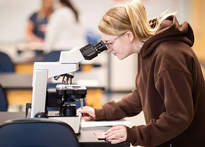 student looking through a microscop in a lab classroom