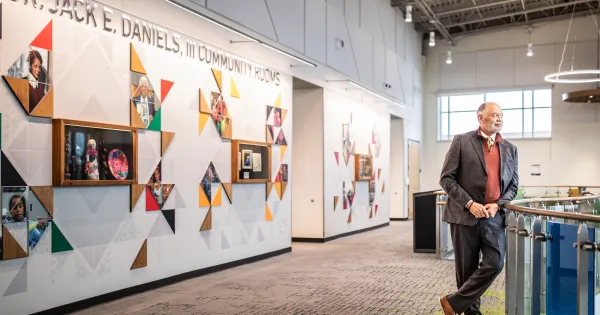 President Daniels stands in front of a wall dedicated to him at the Madison College Goodman South campus.
