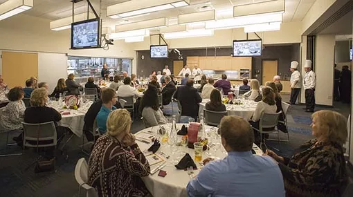 Room full of round tables with people seating at them.