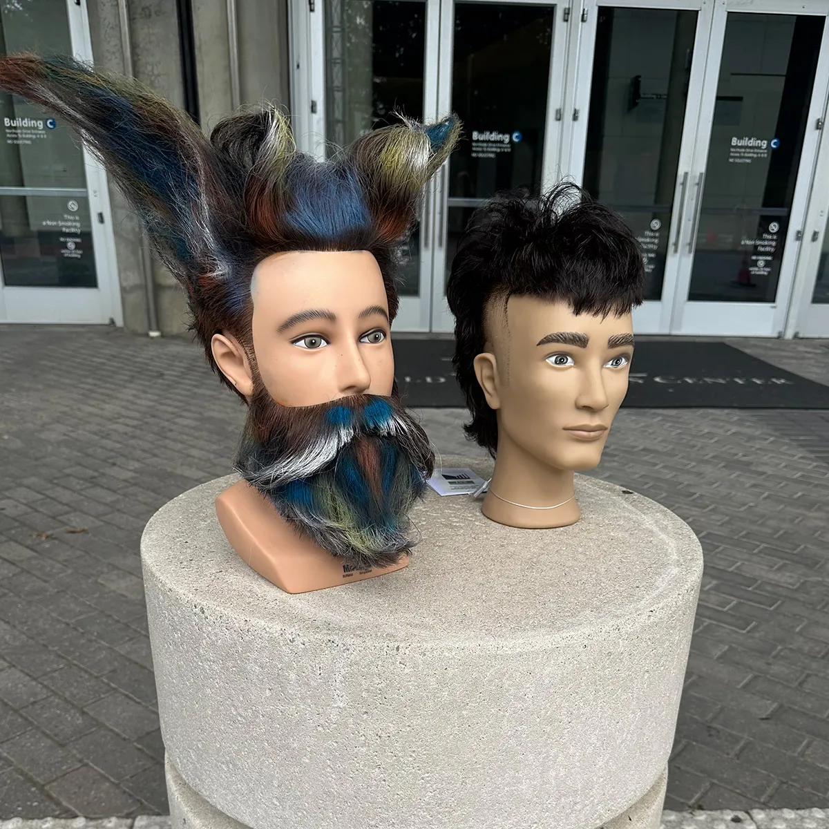 two mannequin heads on display one with a punk hairstyle, the other looks like a manta ray