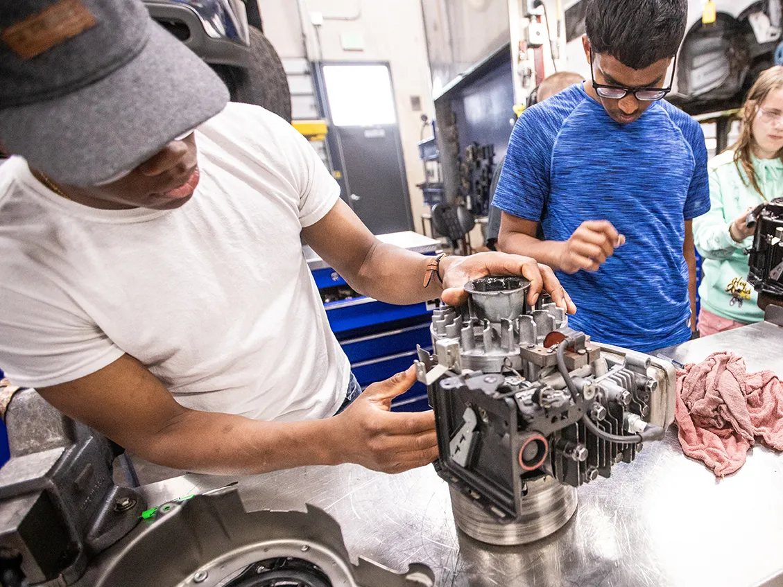 Stem academy students looking at a machine part