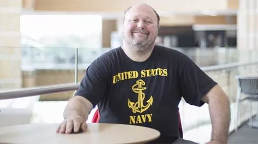 veteran (William) sitting at table in Madison College gateway