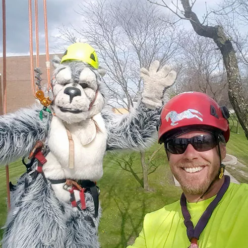 Wolfie mascot and a tree care specialist in a tree